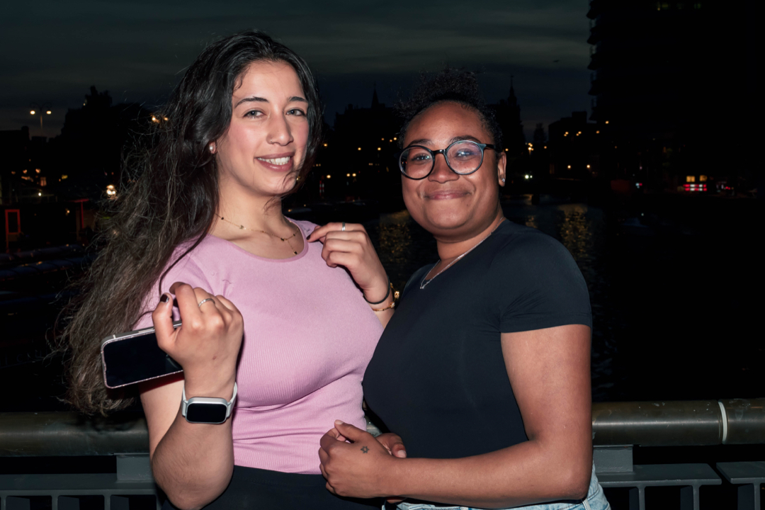 Night fashion portrait of two women standing by the waterfront