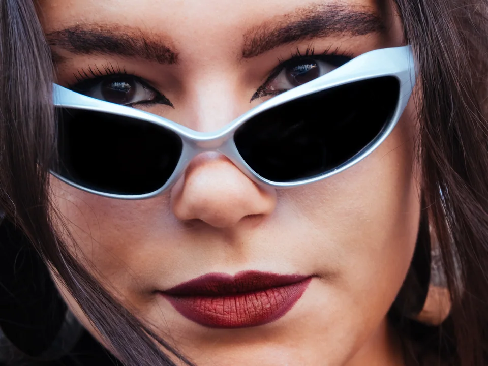 Close-up portrait of a woman looking over white sunglasses